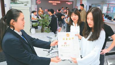 河北省承德市網(wǎng)絡(luò)代購(gòu)經(jīng)營(yíng)者陳晨(右)從工作人員手中接過(guò)帶有統(tǒng)一社會(huì)信用代碼的營(yíng)業(yè)執(zhí)照。 劉環(huán)宇攝(人民圖片)