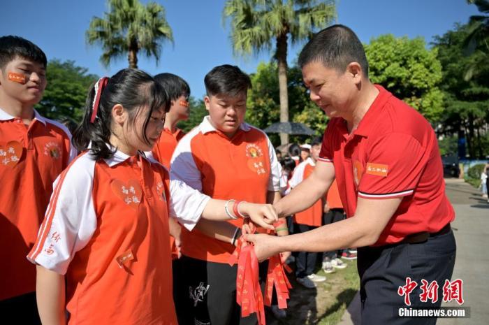 資料圖：廣西華僑實(shí)驗(yàn)高中的教師為高三學(xué)子系上紅絲帶，盼望學(xué)子高考必勝。 俞靖 攝