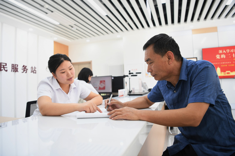2023年5月23日，河北雄安新區(qū)容東片區(qū)南文營社區(qū)居民（右）在社區(qū)便民服務站辦理業(yè)務。